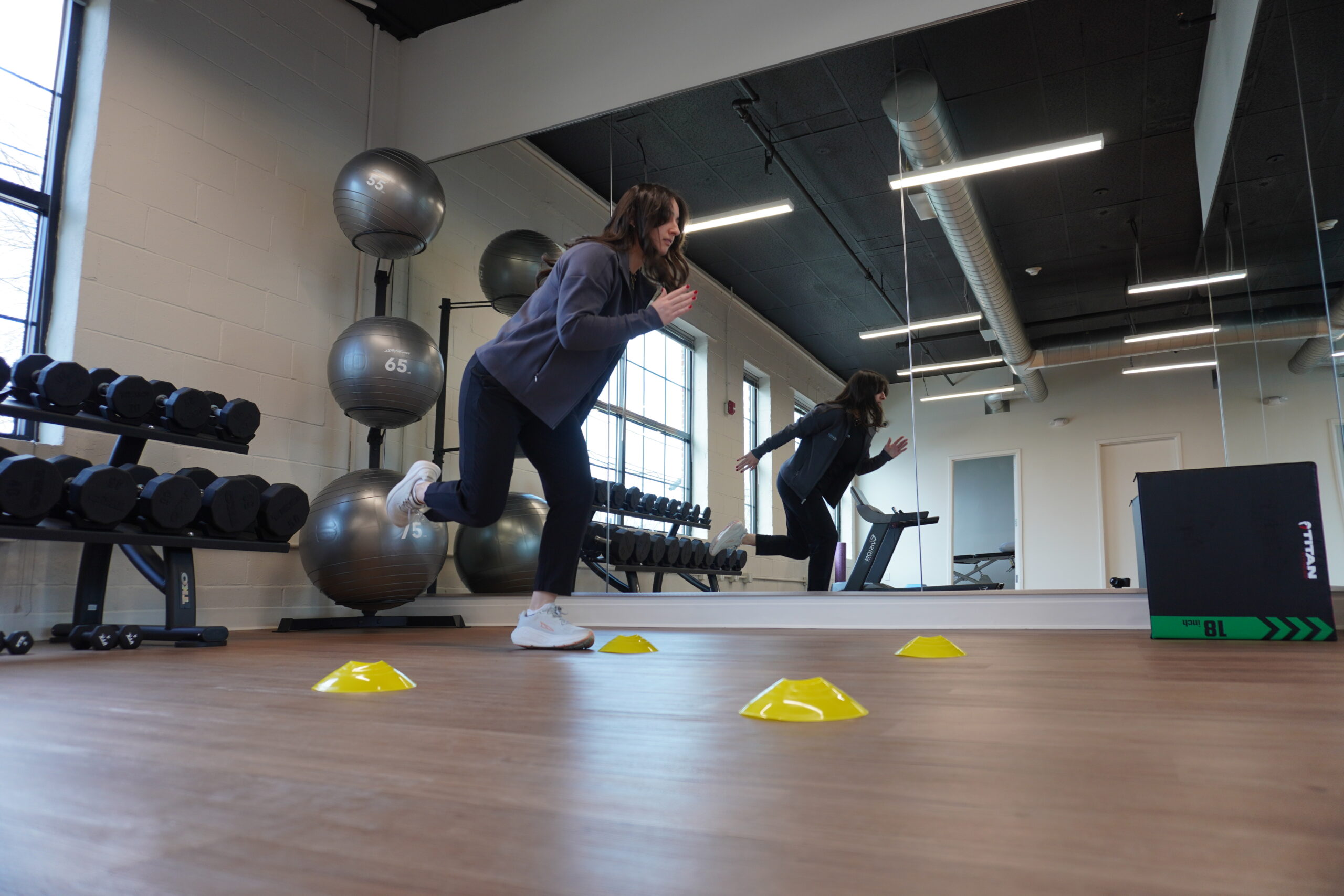 Plyometric exercise includes jumping, running, hopping, skipping. This photo is an example of plyometric exercise in the form of jumping from cone to cone, training reactivity, speed, and explosiveness.
